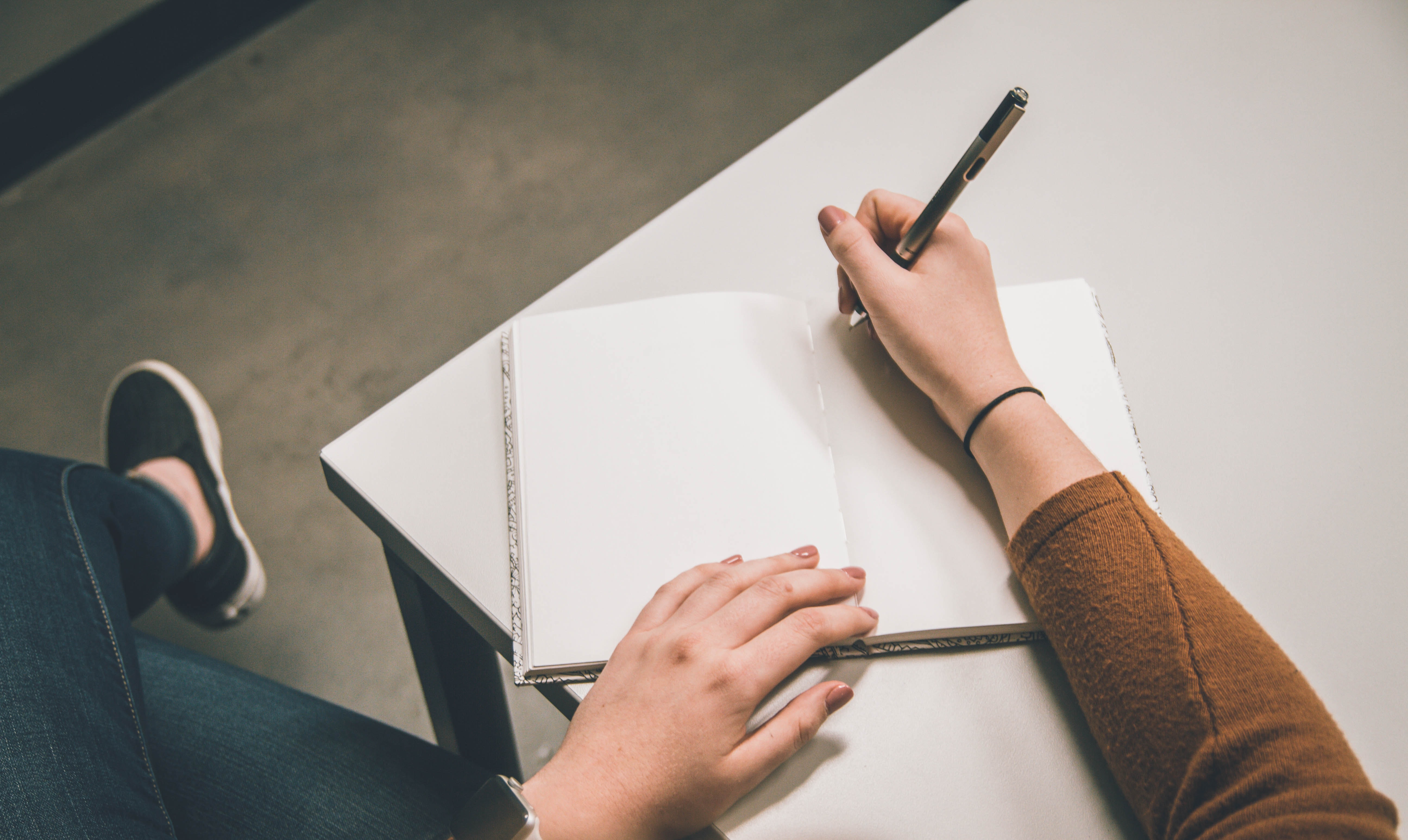 Person sitting at desk writing on a blank page